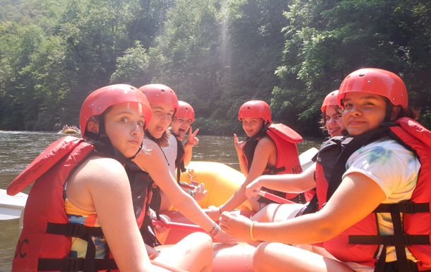 Girl Scouts whitewater rafting in life vests and helmets