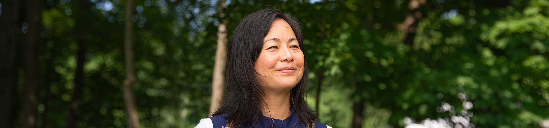  girl scout staff wearing adult uniform vest in woods smiling 