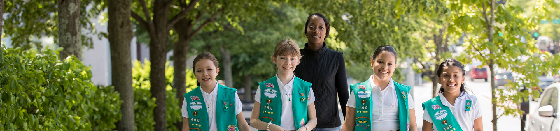 Girl Scout volunteer and Junior Girl Scouts walking outside 