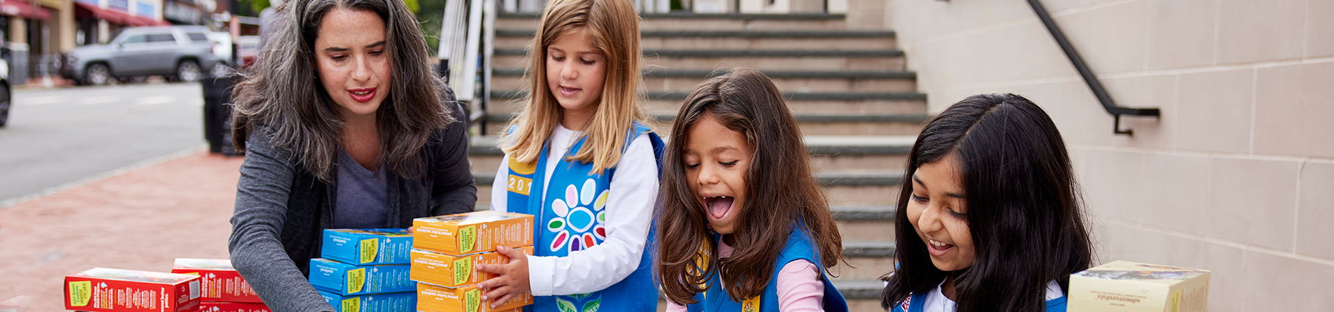  Daisy Girl Scouts and volunteer setting up cookie booth 