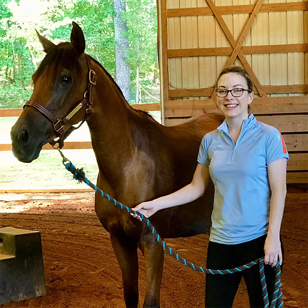 teen riding instructor-in-training next to horse