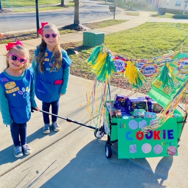 Girl Scout Daisies selling cookies from a wagon