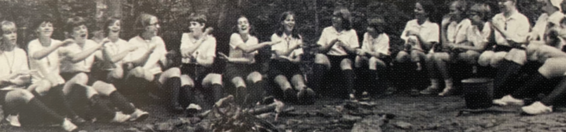  group of girl scouts singing around a campfire at camp pisgah 